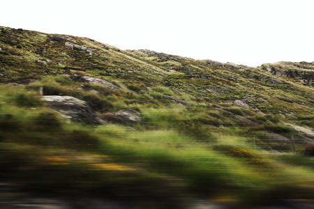 Defocused hills viewed through a car windscreen. Toned filter photo. Blurred action from car at high...