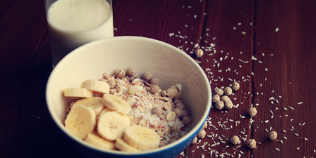 Healthy breakfast. Granola bowl with banana, raisins and nuts. And a glass of milk on the wooden background. Close up photo. Sweet vegan dish. Morning oatmeal closeup.の写真素材
