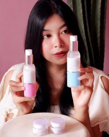 Beautiful asian woman holding a beauty skincare product with closeup portraitの写真素材