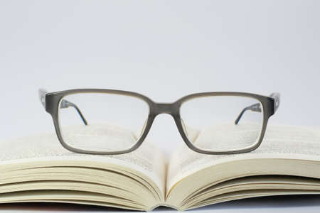 Photo of reading glasses placed on an open bookの写真素材
