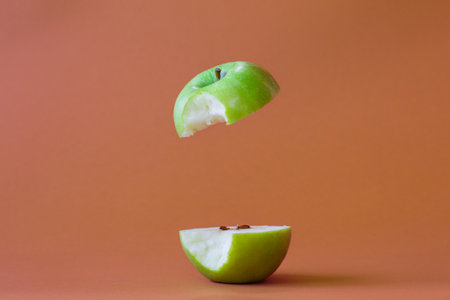 Photo of a green apple cut in half bitten off on the side