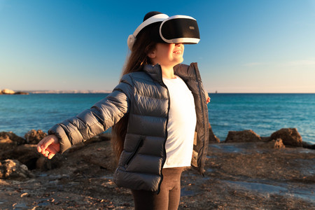 Happy girl with open arms, 3d virtual reality headset on the beach.
