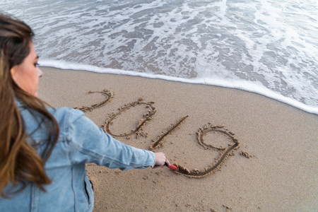 Girl writing 2019 on the sand while enjoying the seaの写真素材