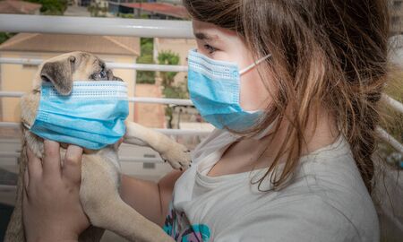 Child with her pet wearing surgical masks during the COVID-19 quarantineの写真素材
