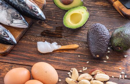 Close up of ketogenic food: MCT oil, mackerel fish, avocado, eggs, coconut butter, Brazilian nuts, radishes, Omega-3 supplements on a wooden tableの写真素材