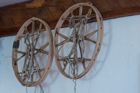Two old wooden wheel on a white wall in a mountain hut, Dolomites, Italyの写真素材