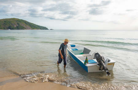 PARATY, RIO DE JANEIRO, BRAZIL - DECEMBER 29, 2019: Man with a hat next to boat in Praia Do Sono, Paraty, Brazil. Paraty is located on the Costa Verde (Green Coast), a lush green corridor in the state of Rio de Janeiro.のeditorial素材