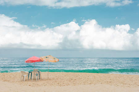 PARATY, RIO DE JANEIRO, BRAZIL - DECEMBER 27, 2019: Beach chair and umbrella in beautiful scenery with sand, blue sea and cloudy sky in Trindade, Paraty, Brazil. Paraty is located on the Costa Verde (Green Coast), a lush green corridor in the state of Rioのeditorial素材