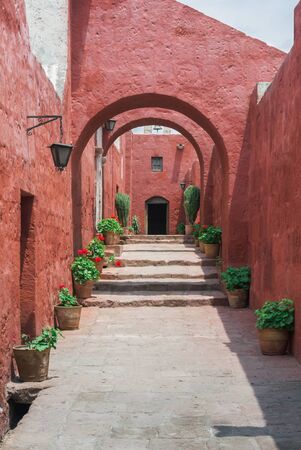 Beautiful narrow street with flower pots and red colonial buildings in Monastery of Santa Catalina, Arequipa, Peruの写真素材