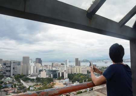 RIO DE JANEIRO, BRAZIL - JANUARY 3, 2020: Unidentified woman with a mobile phone looks the panoramic...