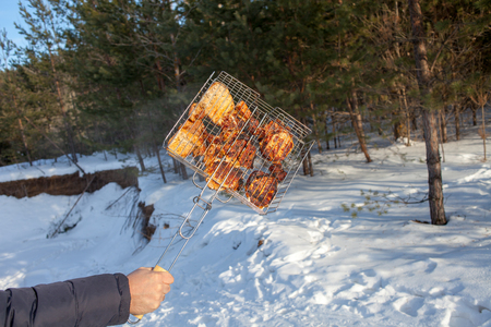 The person who is grilling the pork or beef on the grill or grille, man holding a grill with meat winterの写真素材