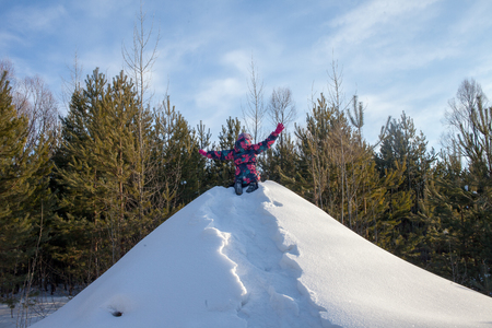 child climb the hill with a tube for descent. Children ski in the winter with a slide on the tubing. kid runs to hill and sledding down by the tube. winter leisure the child climbed a snowy mountain in the forestの写真素材