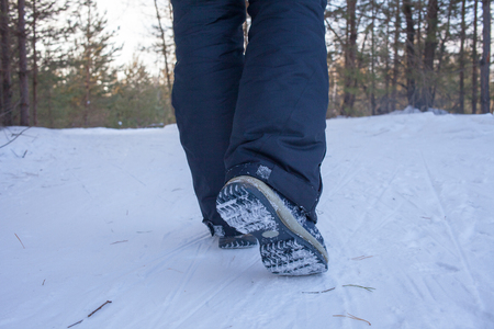 Woman legs in boots close up the snow-covered path in the winter forest, rear view legs in the forest in winterの写真素材