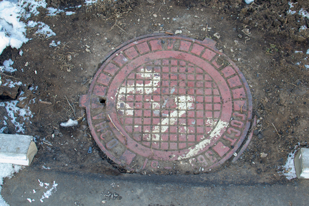 Sewer manhole on the road in winterの写真素材