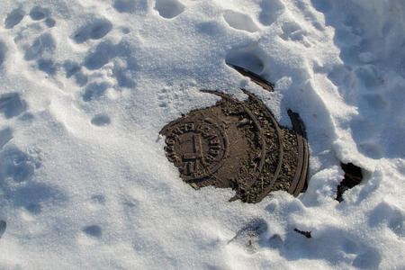Sewer manhole on the road in winterの写真素材