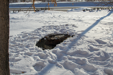 Sewer manhole on the road in winterの写真素材