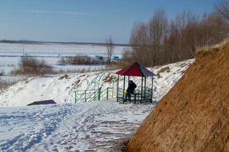 a man sits on the Bank of a frozen riverの写真素材