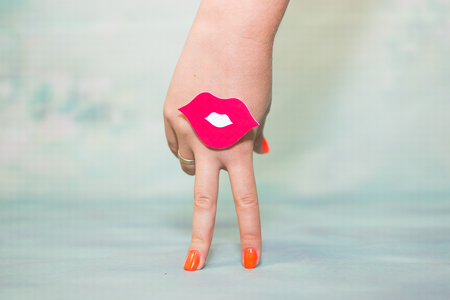 Female hand with two fingers down smile and red lips on blue backgroundの写真素材