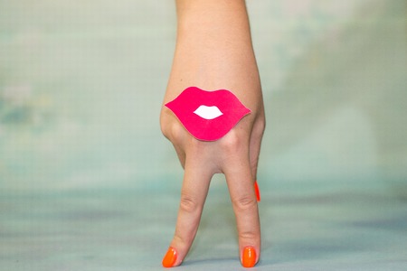 Female hand with two fingers down smile and red lips on blue backgroundの写真素材