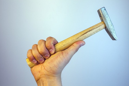 Close-up view of a man's hand holding hammer, isolated on white background. Repairing and maintenance. Building and destroying.の写真素材