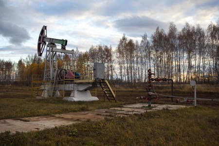 In the evening. The oil pump, industrial equipment. Oil field site, oil pumps are running. Rocking...