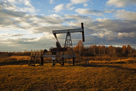 In the evening. The oil pump, industrial equipment. Oil field site, oil pumps are running. Rocking machines for oil productionの写真素材