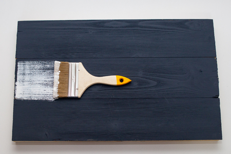 Master paints the Board with white paint. Create fotofone for advertising from wood. Toning the Board with white paint. White paint on black paint. Create fotofoneの写真素材