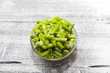 Frozen beans. Glass bowl with frozen green beans on beautiful wooden background. foodの写真素材