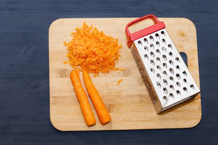 The composition of the grated carrots. grated carrots on a cutting Board. Black wooden backgroundの写真素材