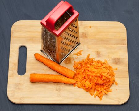 The composition of the grated carrots. grated carrots on a cutting Board. Black wooden backgroundの写真素材