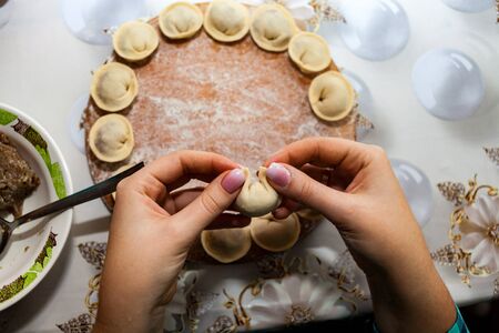 woman preparing dumplings hands. Sculpt pierogy and pelmeni concept. Include rustic cutting board, making pierogies on a rustic wooden table. Dumpling recipe.の写真素材