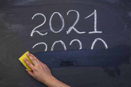 New year 2021. The concept of the new year 2021, the outgoing year 2020. hand erases the inscription 2020 from the Boardの写真素材