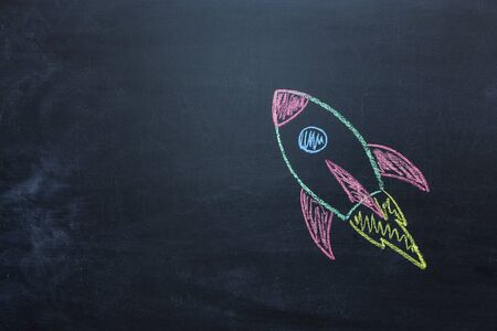 Chalk space rocket painted on school chalkboard.