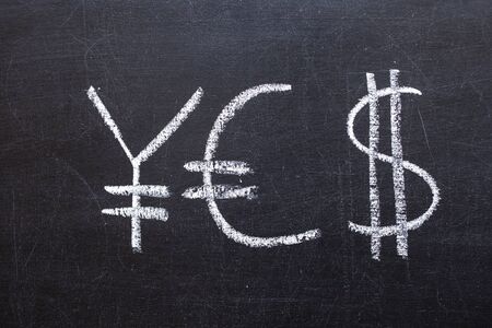 Yen, Euro and Dollar signs written on a chalkboardの写真素材