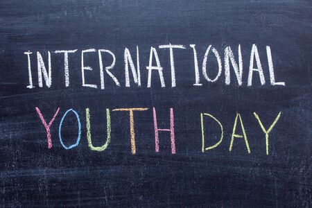 International Youth Day handwritten text in colored chalk on a chalkboard.の写真素材