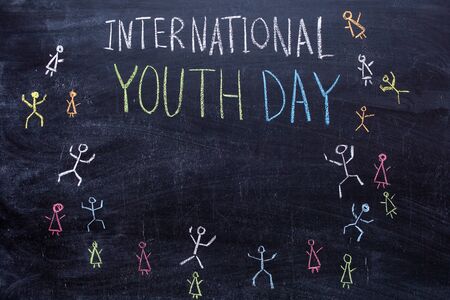 International Youth Day handwritten text in colored chalk on a chalkboard. Drawings of little men on the blackboardの写真素材