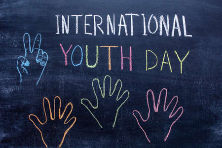 International Youth Day handwritten text in colored chalk on a chalkboard. Palm drawings on the blackboardの写真素材