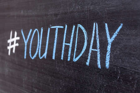 Hashtag YouthDay handwritten text in colored chalk on a chalkboard.の写真素材
