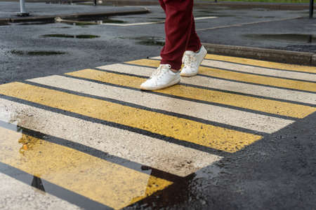 A girl crosses the road at a pedestrian crossingの写真素材