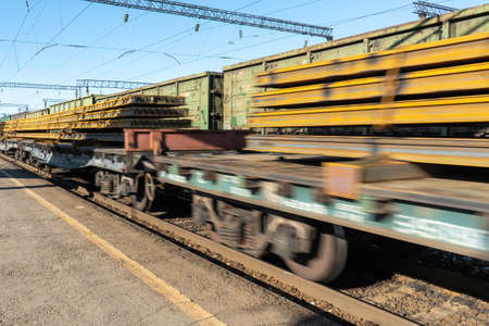 A train carrying rails arrives at the station