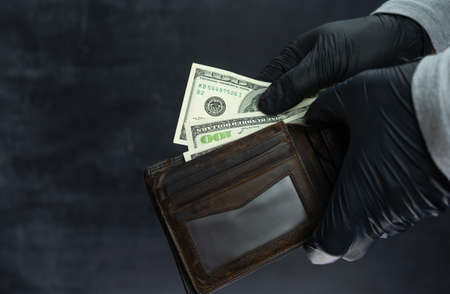 A man in black medical gloves counts the remaining money in his wallet. Hundred-dollar bills in your walletの写真素材