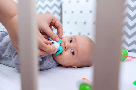 mom tries to give a pacifier to a crying baby. Selective focusの写真素材