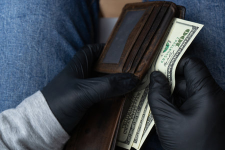 Black-gloved hands count the money in the stolen wallet.
