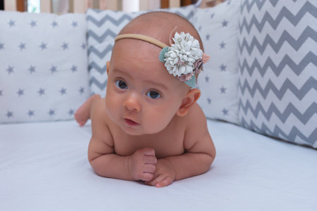 Newborn baby girl learning to crawl in the crib