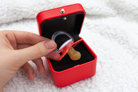 Woman's hand takes a pink pacifier from a red gift boxの写真素材