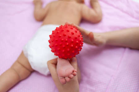 Mom makes a massage with a ball to a newborn baby. Selective focusの写真素材