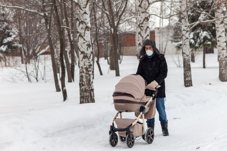 Father walks through the park in winter with a baby carriage, Russiaの写真素材