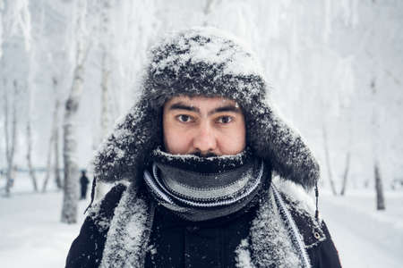 Portrait of a Russian man in a hat and scarf in winter looking at the cameraの写真素材