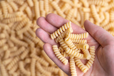 Spiral-shaped pasta in a woman's palm. Fusilli pasta backgroundの写真素材