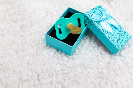 Gift box and pacifier for little boy on white background